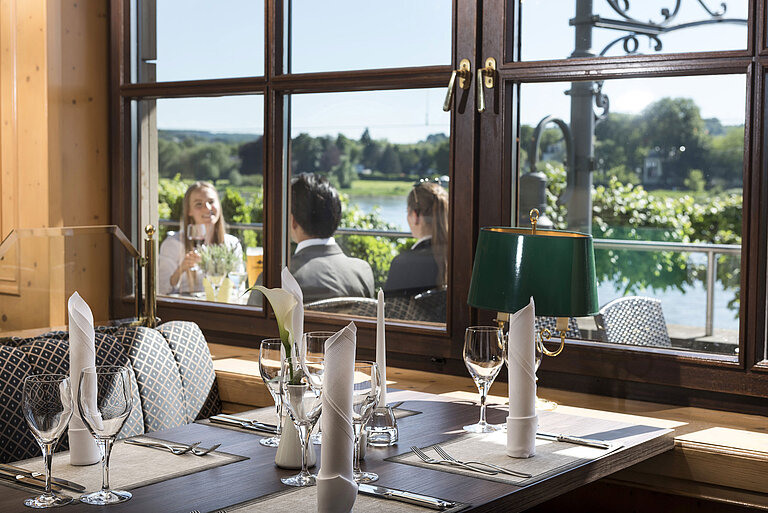 Stylishly set table in the restaurant of Maritim Hotel Königswinter overlooking the Rhine and nature.