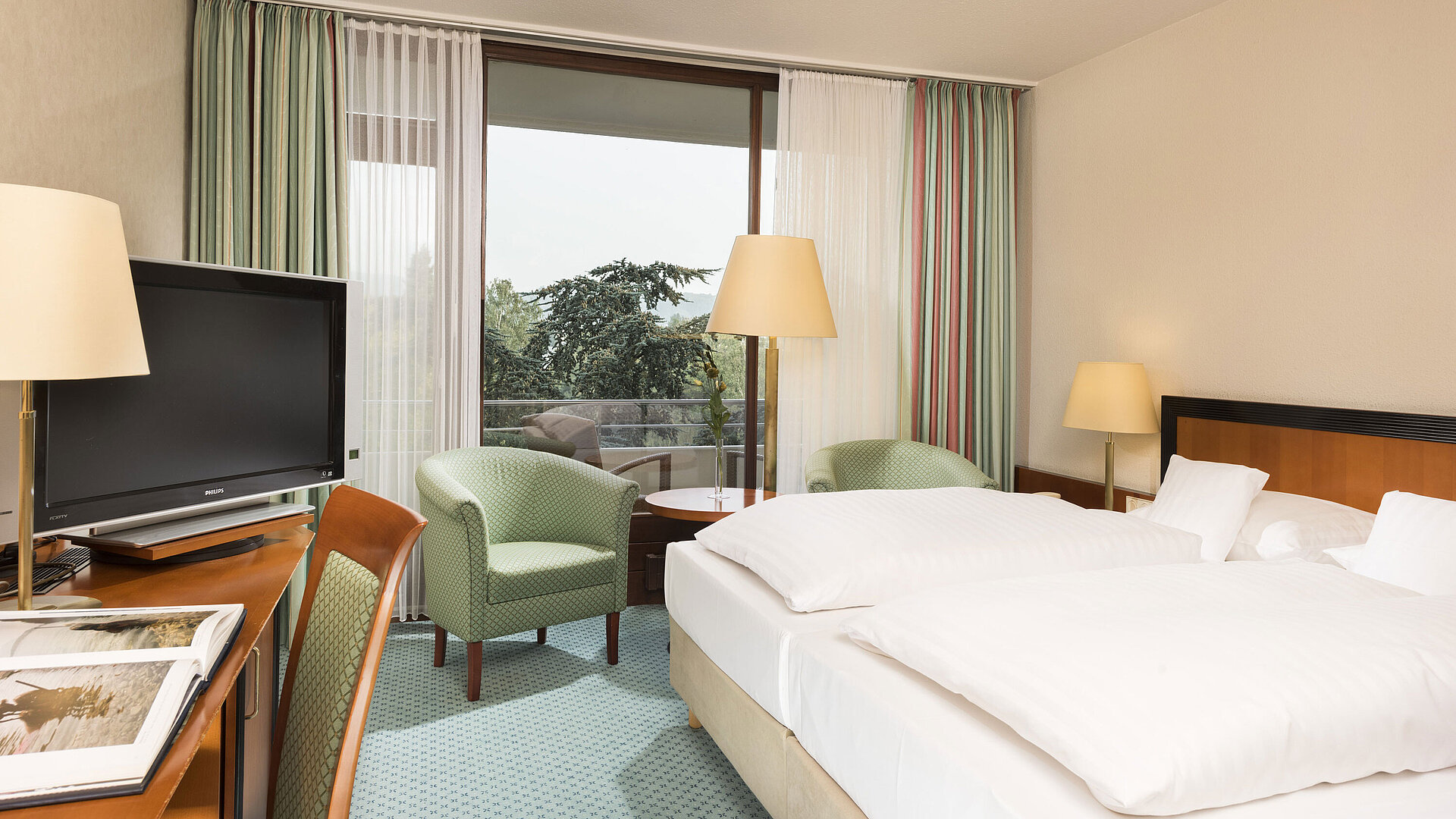 Bright hotel room at Maritim Hotel Bad Salzuflen with double bed, seating area and balcony access