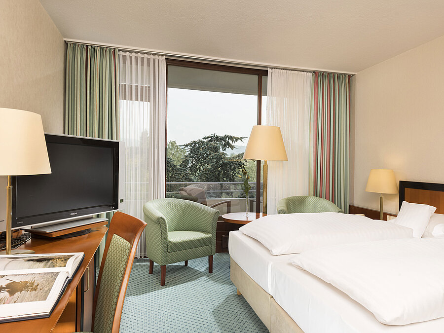 Bright hotel room at Maritim Hotel Bad Salzuflen with double bed, seating area and balcony access