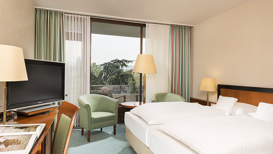 Bright hotel room at Maritim Hotel Bad Salzuflen with double bed, seating area and balcony access