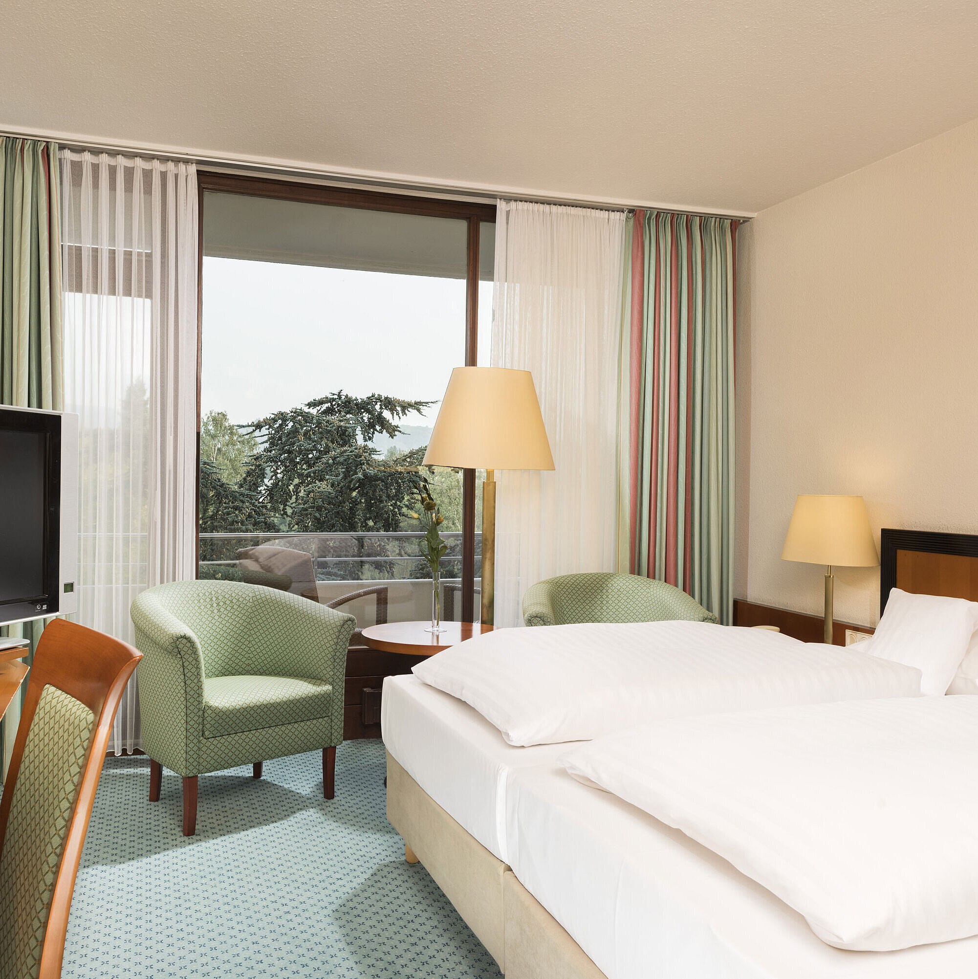 Bright hotel room at Maritim Hotel Bad Salzuflen with double bed, seating area and balcony access