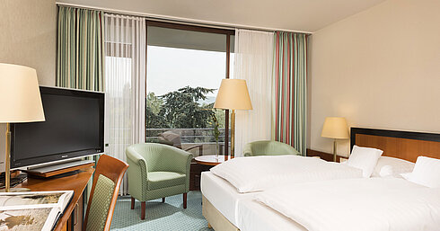 Bright hotel room at Maritim Hotel Bad Salzuflen with double bed, seating area and balcony access