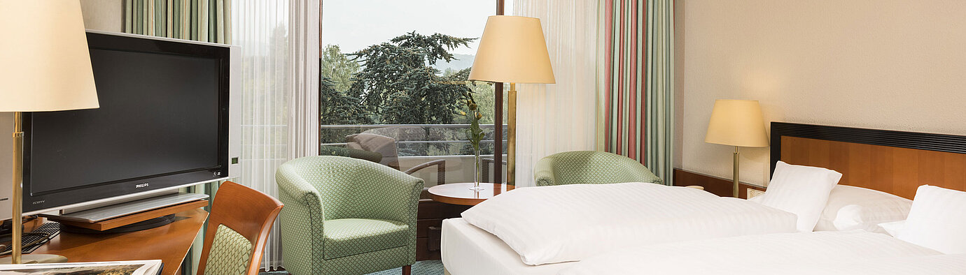 Bright hotel room at Maritim Hotel Bad Salzuflen with double bed, seating area and balcony access