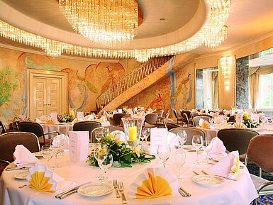 Elegant banquet hall with wall paintings, chandeliers and festively set tables