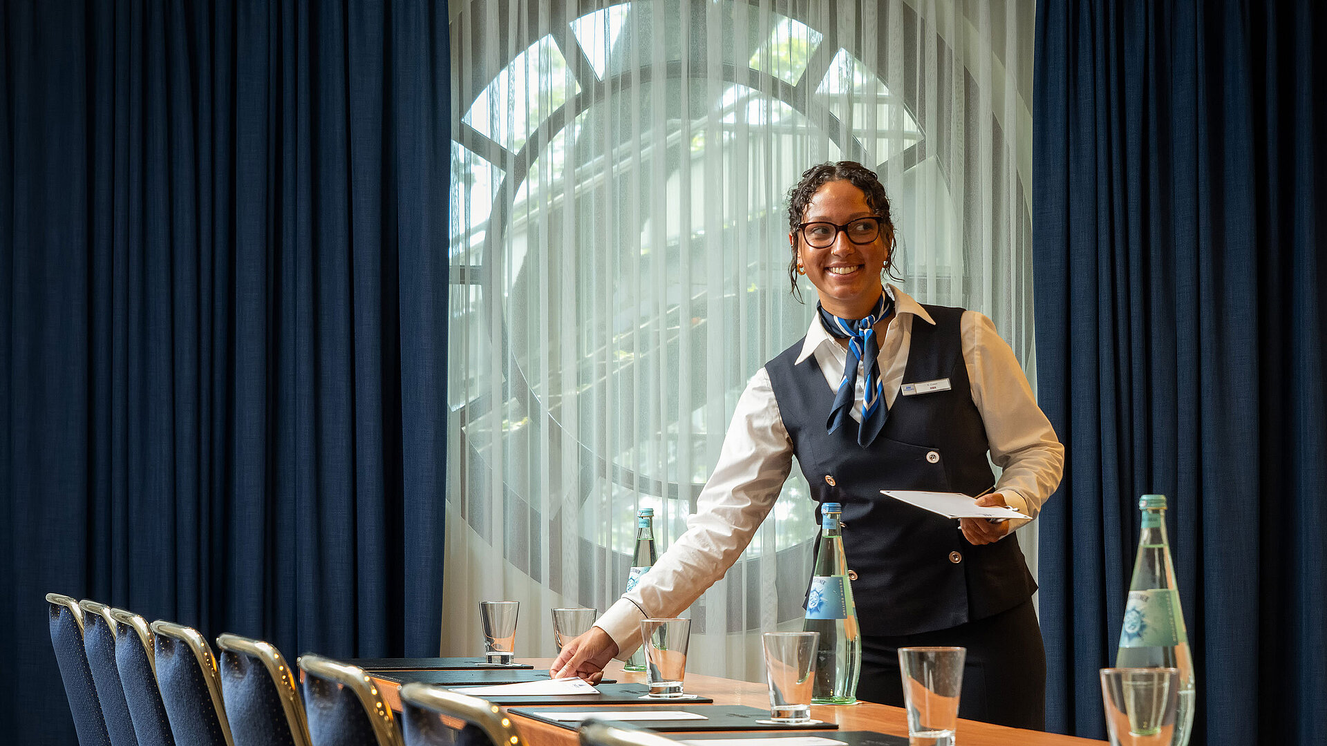 Staff member at Maritim Hotel Köln preparing conference room with drinks and documents