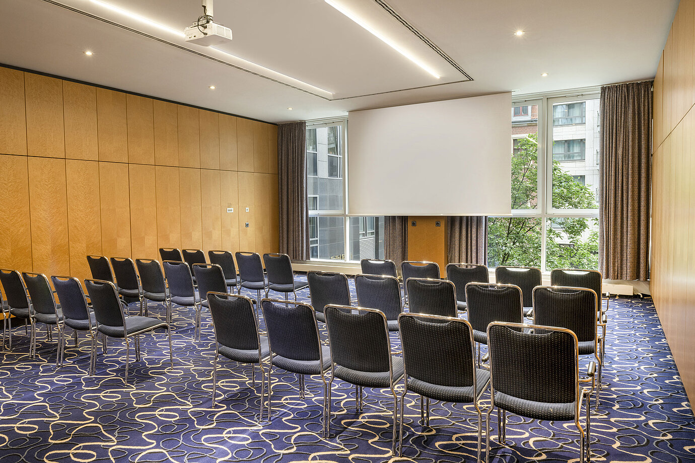 Modern conference room at Maritim proArte Hotel Berlin with rows of chairs and screen.