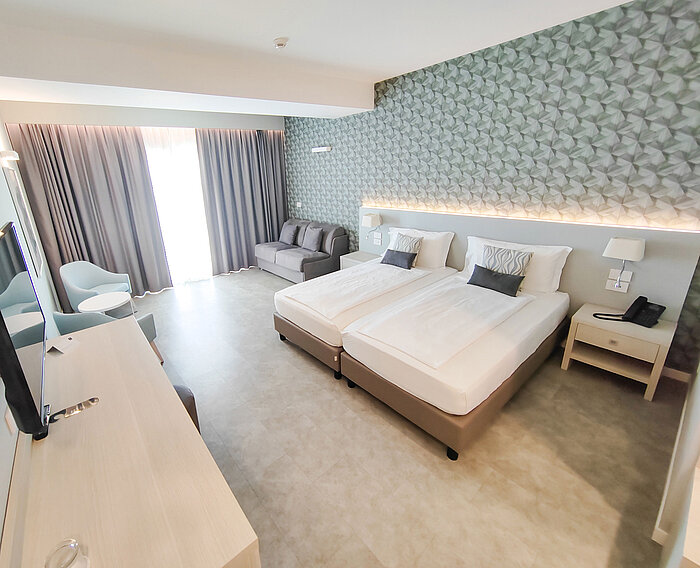 Spacious room at Maritim Resort Calabria with twin bed, sofa, desk and bright design