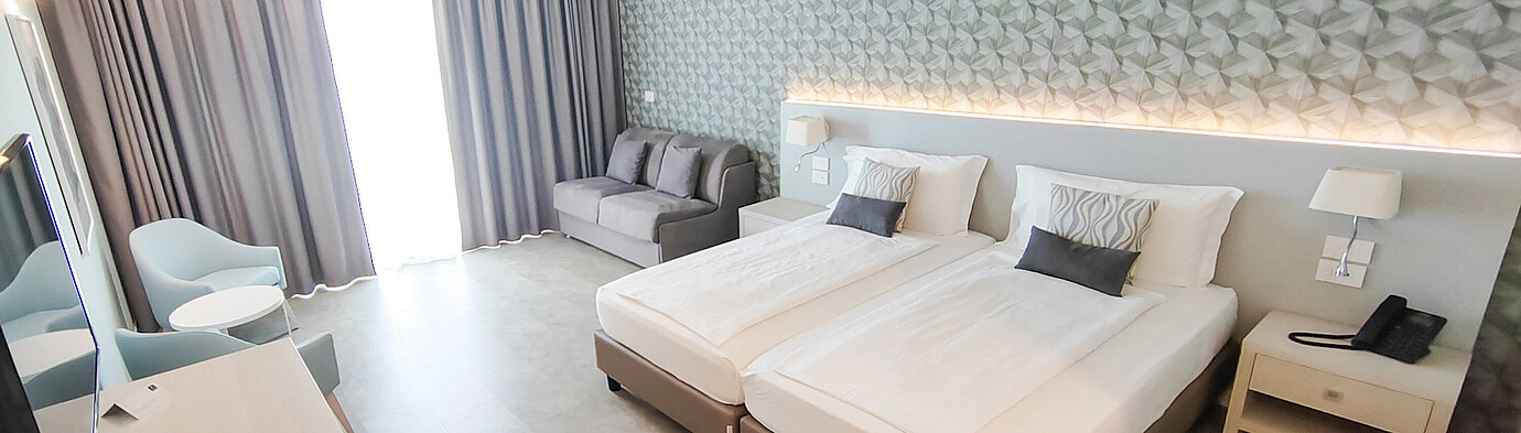 Spacious room at Maritim Resort Calabria with twin bed, sofa, desk and bright design