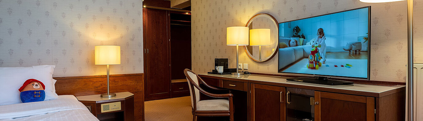 Superior family room with bed, large TV, desk and cosy seating area for a comfortable stay.