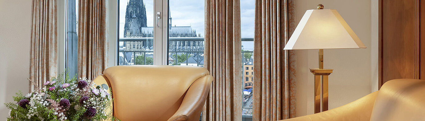  Elegant Heumarkt Suite at Maritim Hotel Cologne featuring comfortable leather chairs and a direct view of Cologne Cathedral.