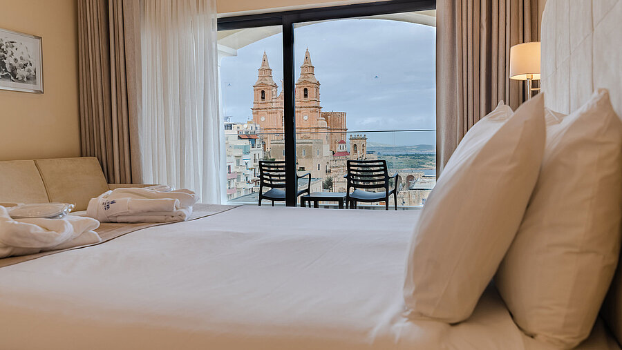 Hotel room with double bed, balcony and views of historic church and city