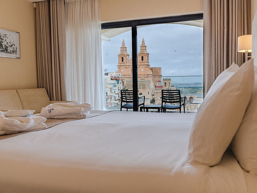 Hotel room with double bed, balcony and views of historic church and city