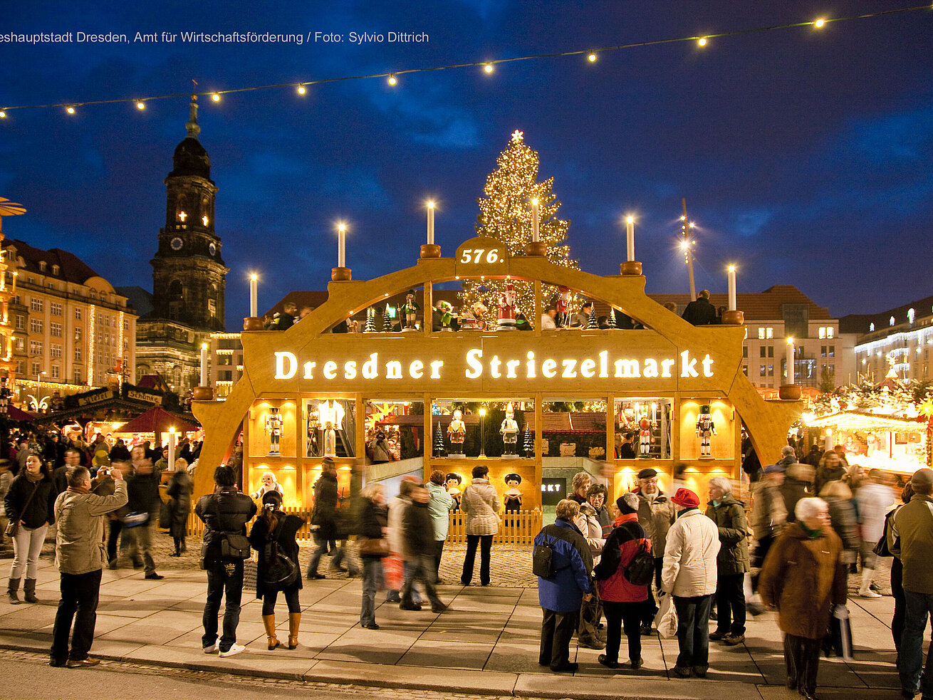 Dresden Striezelmarkt with Christmas tree lights and many visitors in the evening