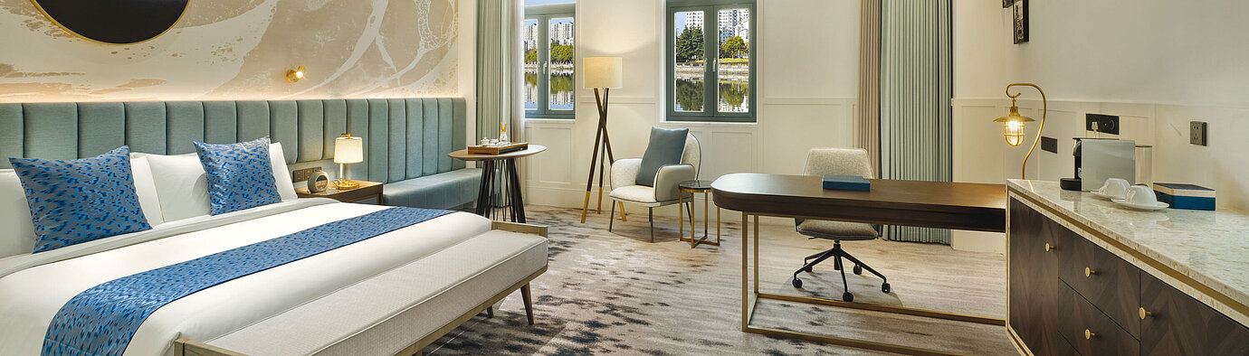 Modern hotel room with large workspace, seating area and serene lake view at Maritim Hotel Taicang