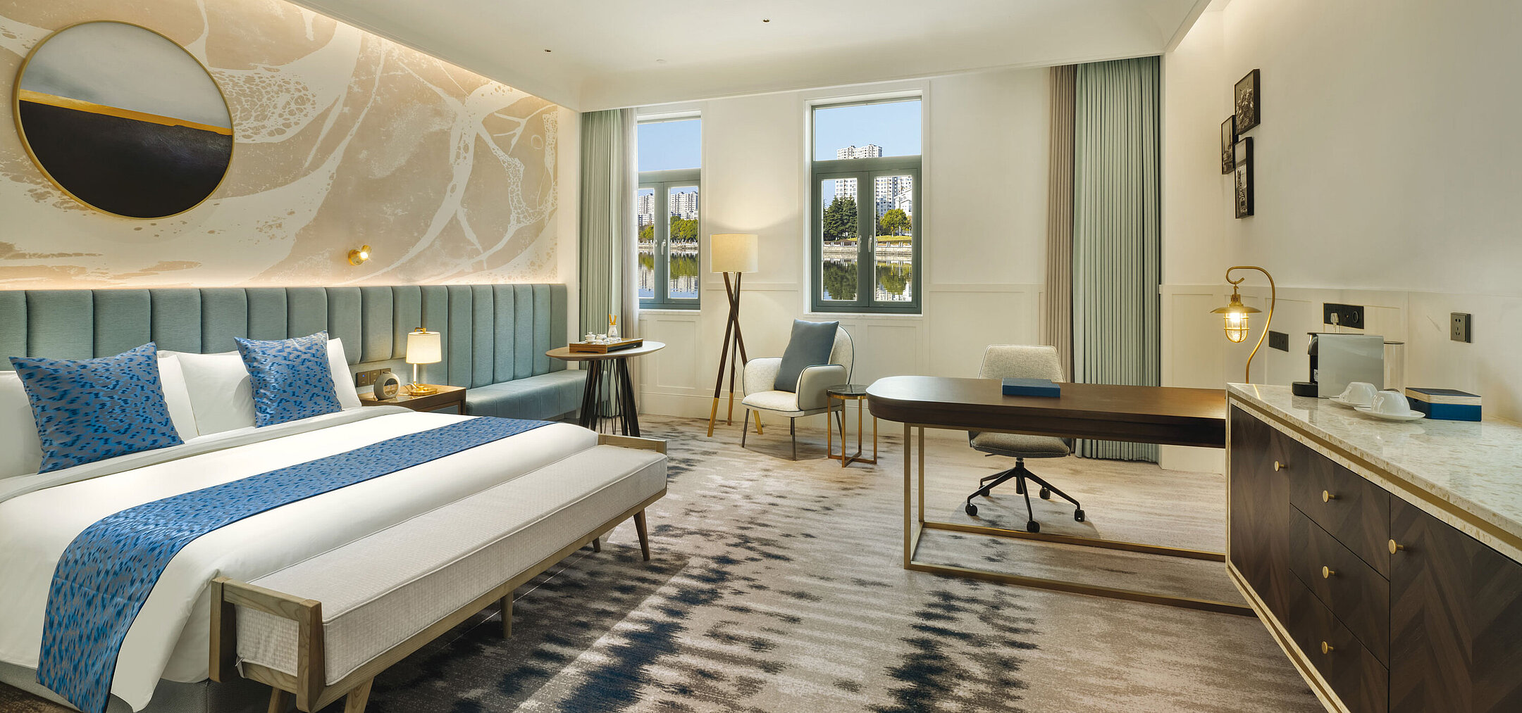 Modern hotel room with large workspace, seating area and serene lake view at Maritim Hotel Taicang