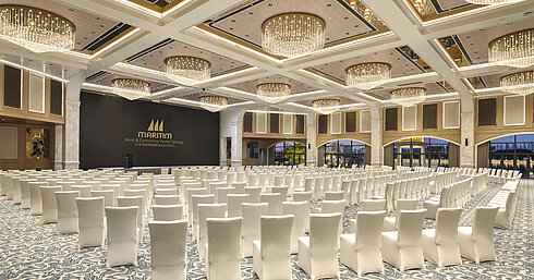 Large conference hall at Maritim Hotel with white theatre seating, high ceilings and modern chandeliers