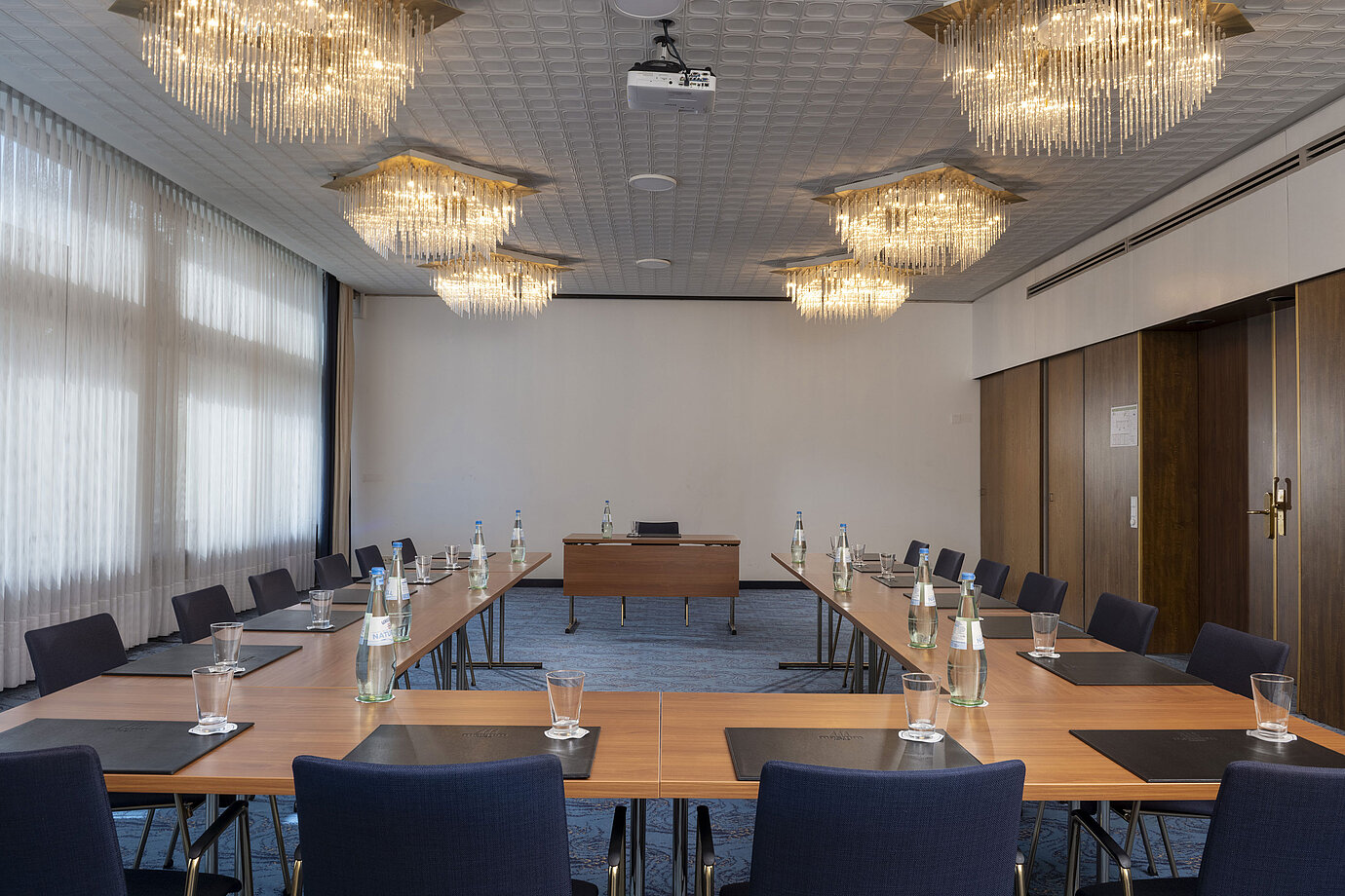 Stylish room with U-shape seating and chandeliers at Maritim Hotel Travemünde