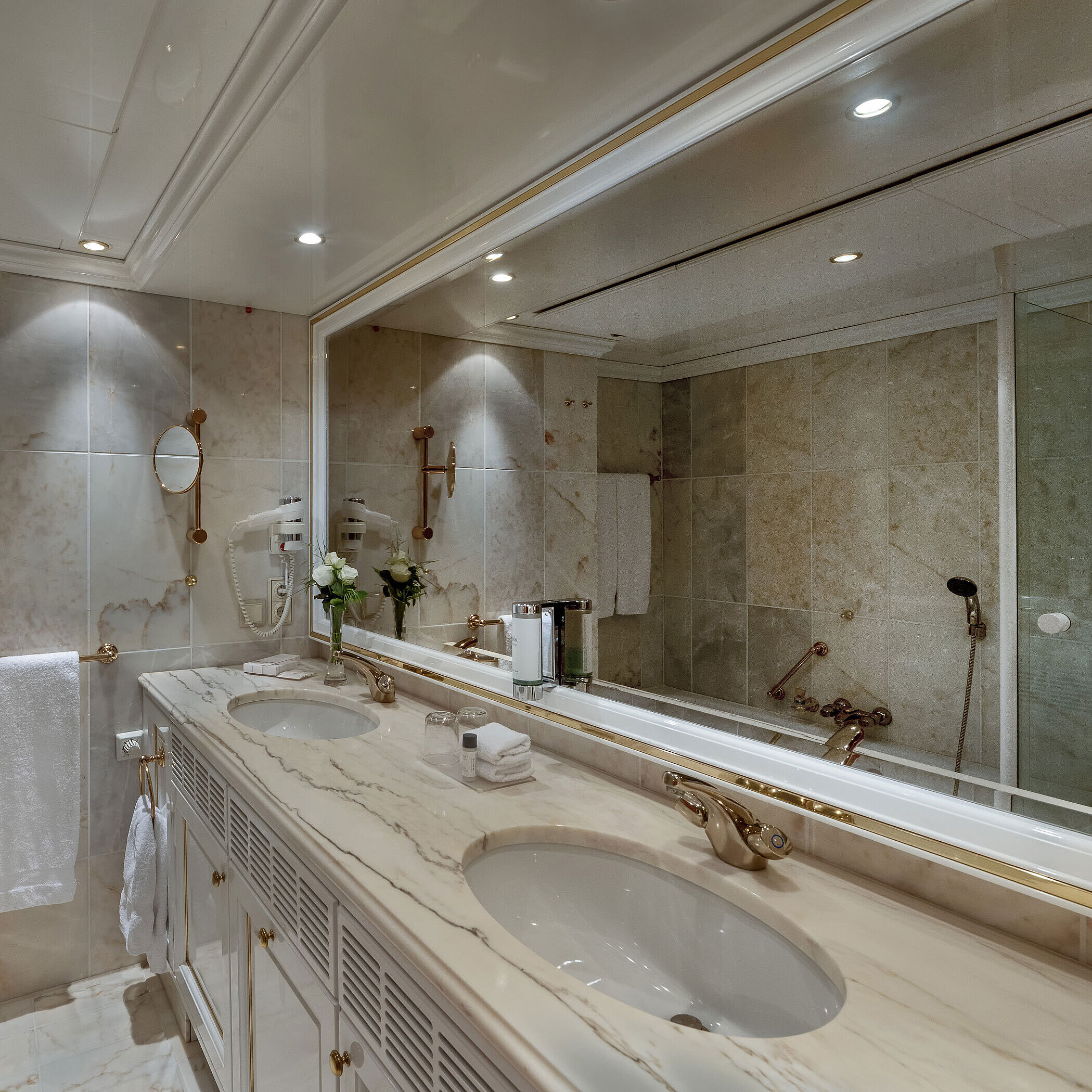 Marble bathroom in the Maritim Airport Hotel Hannover with double vanity, mirror, and bathtub.