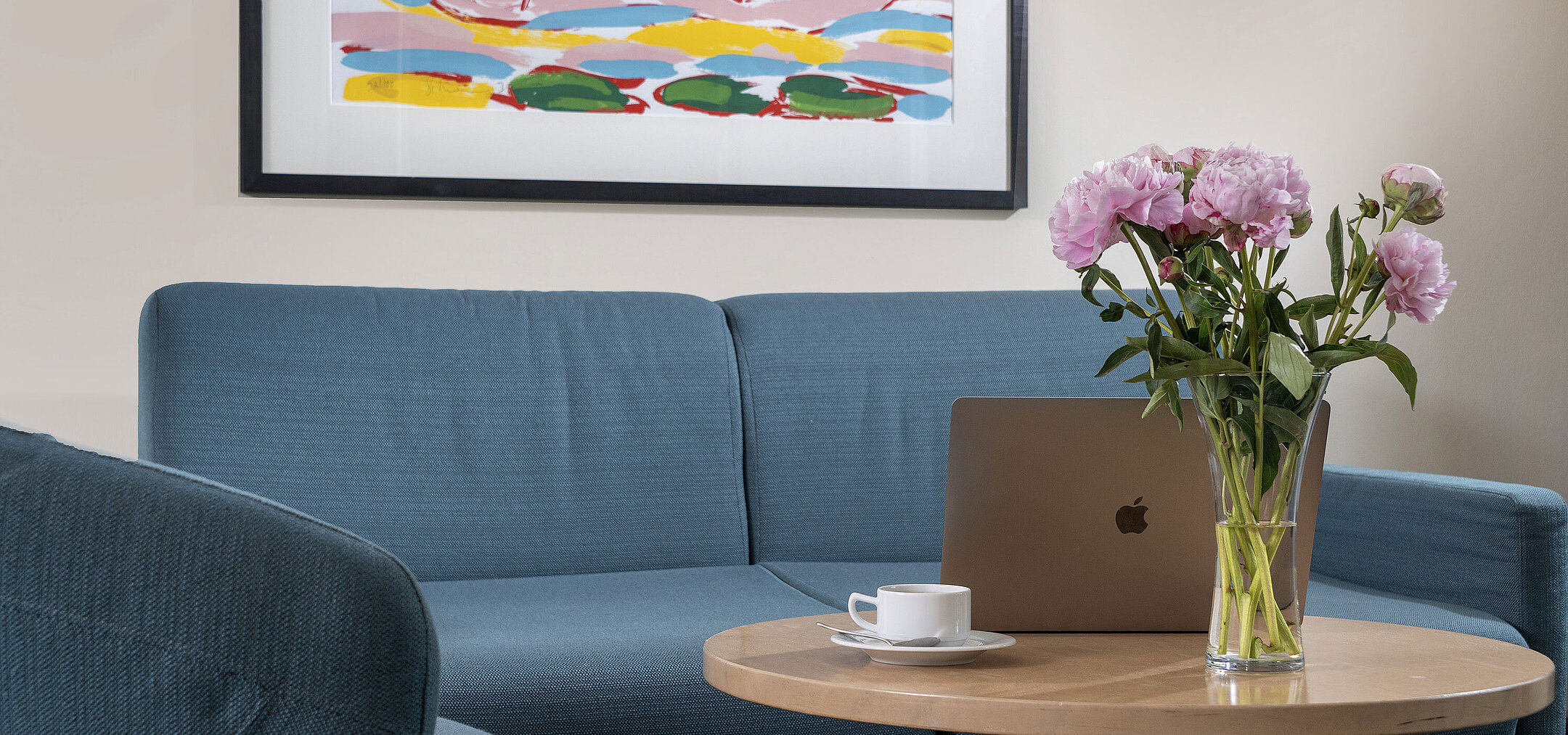 Modern living area with sofa, coffee table, flowers and laptop at Maritim proArte Hotel Berlin