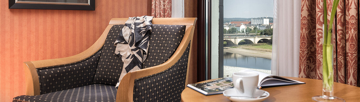 Cozy armchair detail with a view of the Elbe River and bridge, decorated with a scarf on the backrestCozy armchair detail at Maritim Hotel Dresden with a view of the Elbe River and bridge, decorated with a scarf on the backrestCozy armchair detail at Maritim Hotel Dresden with a view of the Elbe River and bridge, decorated with a scarf on the backrestCozy armchair detail at Maritim Hotel Dresden with a view of the Elbe River and bridge, decorated with a scarf on the backrest.