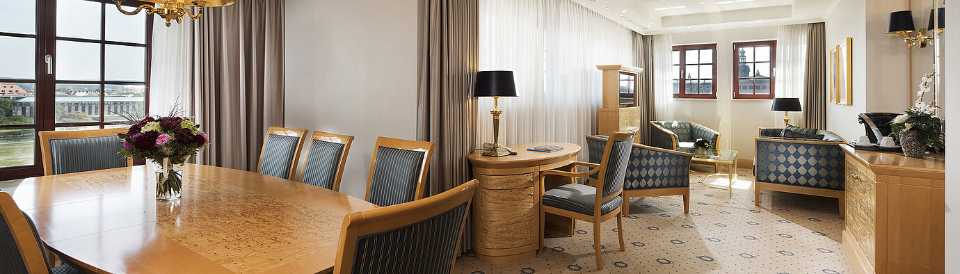 Spacious Executive Suite at Maritim Hotel Dresden with elegant dining table, comfortable seating area, and city view.
