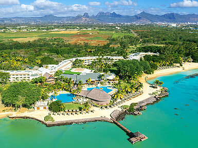 Aerial view of a tropical beach resort with pools, palm trees and direct access to turquoise sea