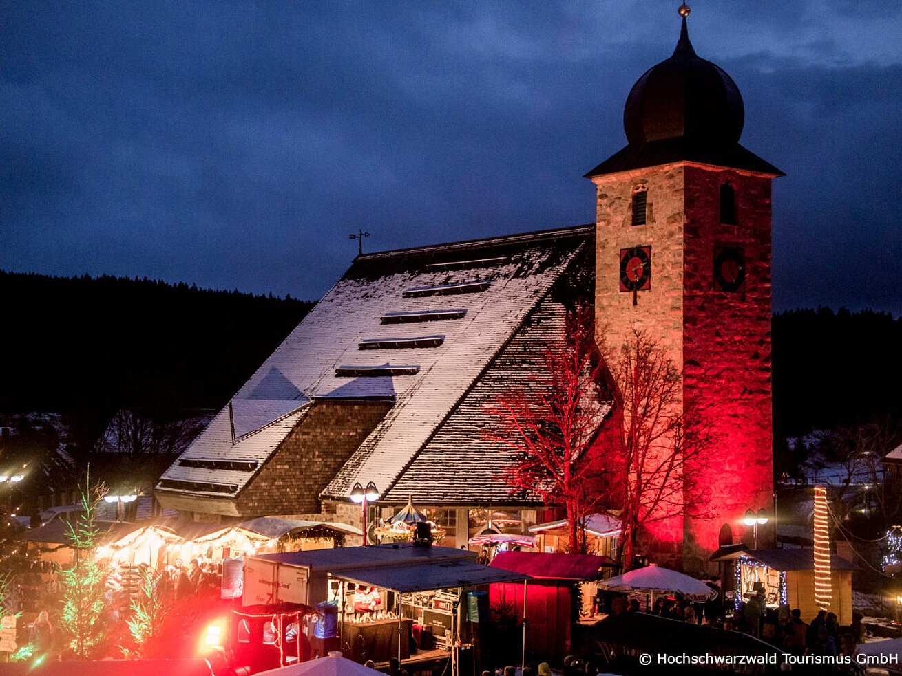 Winter market at Schluchsee with illuminated church, stalls and festive evening atmosphere.