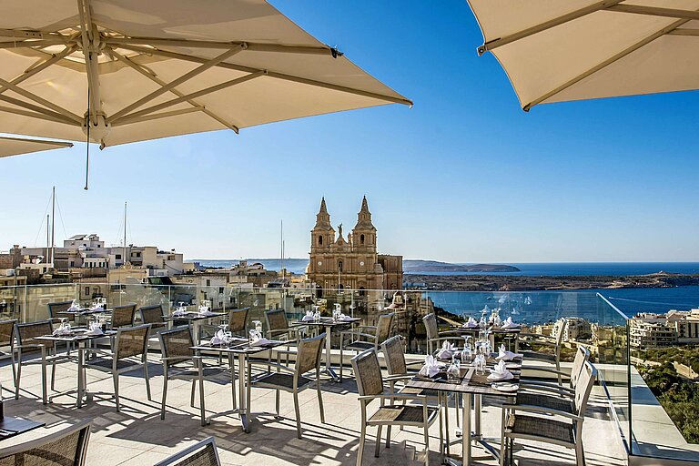 Rooftop terrace with restaurant seating, parasols and views of church and sea