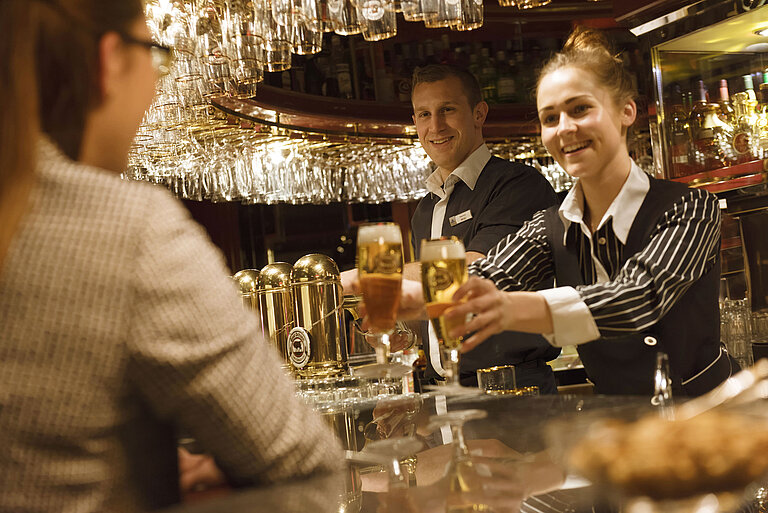 Two staff members serve freshly tapped drinks at the bar at the Maritim Hotel Ulm