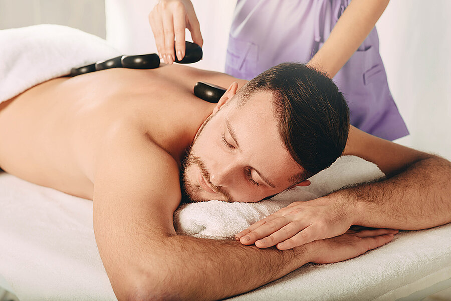 Man enjoying relaxing hot stone massage in spa for deep relaxation