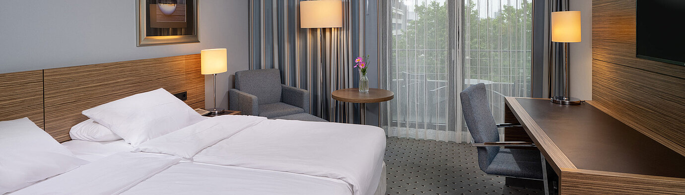 Full view of the Comfort room at the Maritim Hotel Darmstadt with a bed, desk, and balcony access