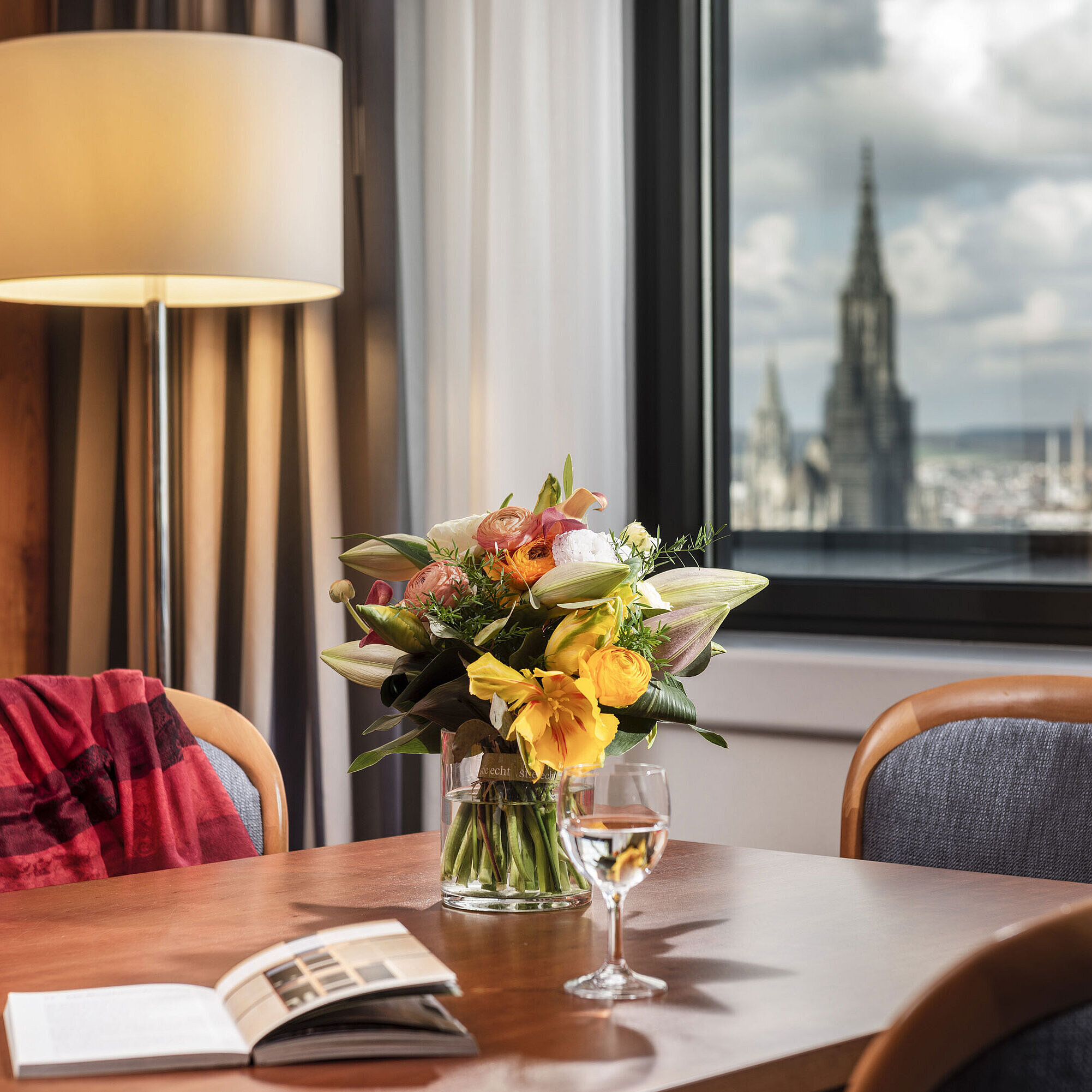 Table with flower bouquet in Junior Suite at Maritim Hotel Ulm with a view of Ulm Minster