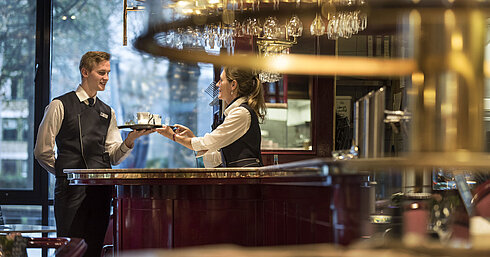 Friendly service staff at the Brasserie bar of Maritim Hotel Bonn, offering beverage service with a smile.