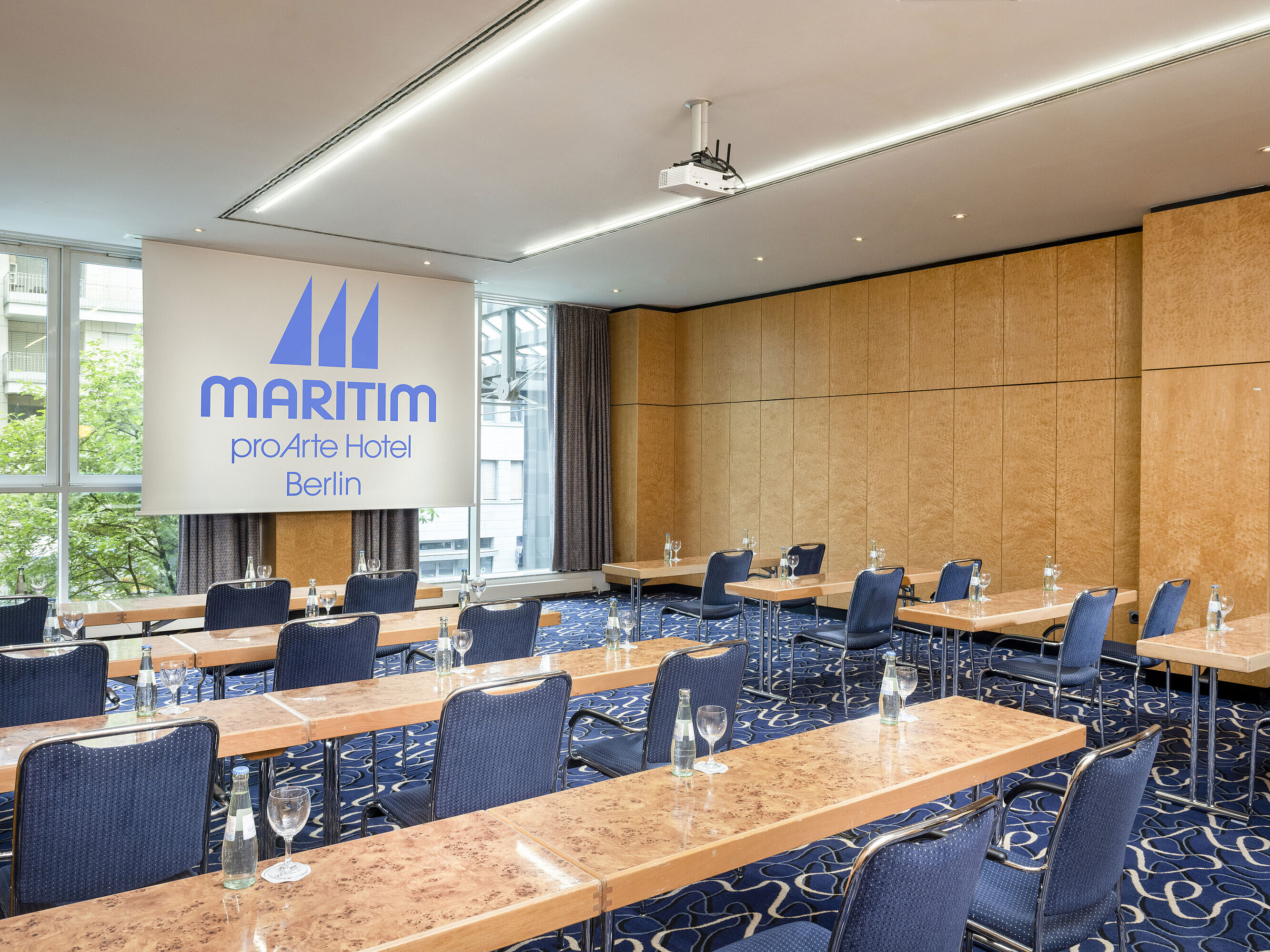 Conference room at Maritim proArte Hotel Berlin with row seating and projection screen.
