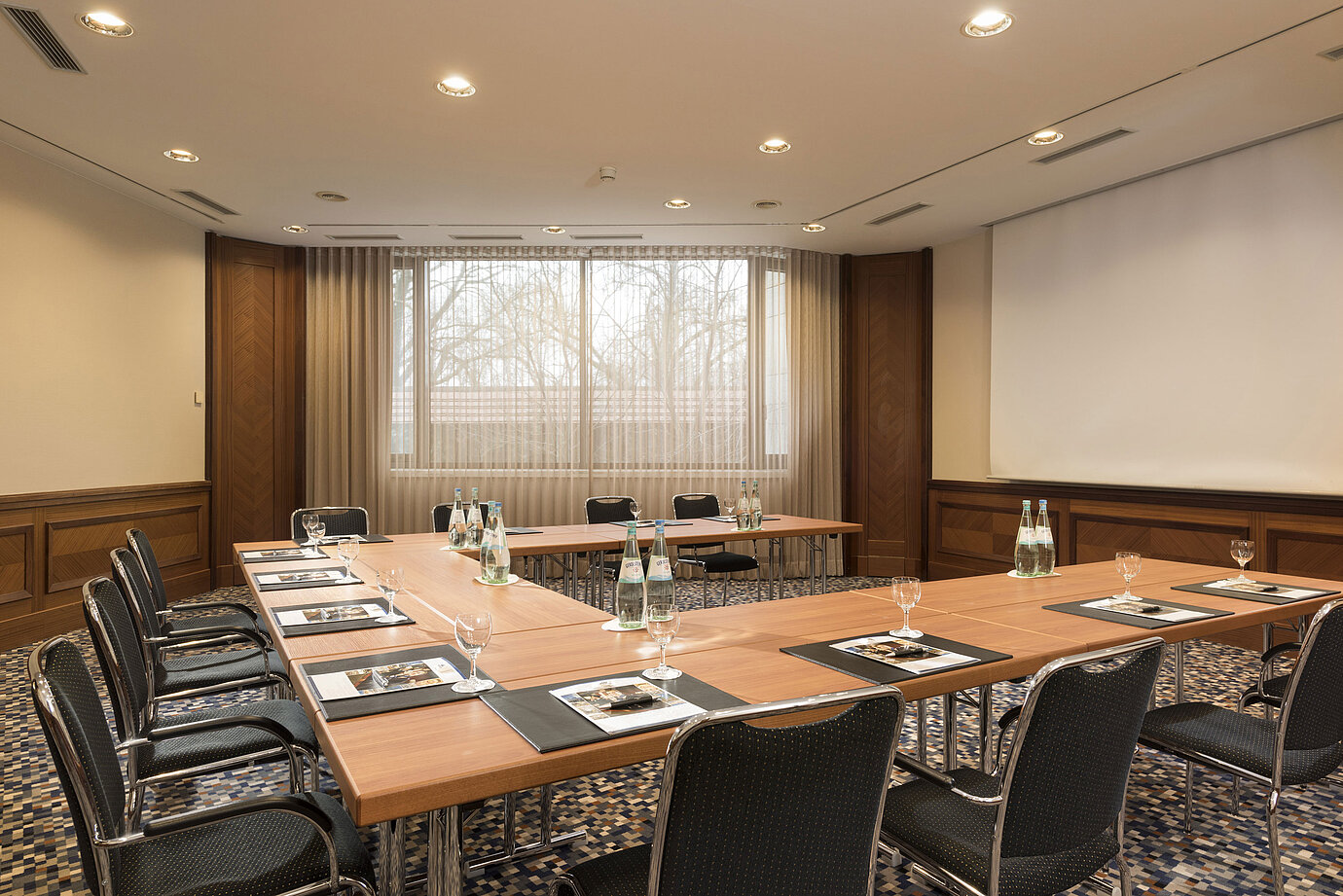 Bright conference room with U-shape seating, window front and screen at Maritim Hotel Ulm.