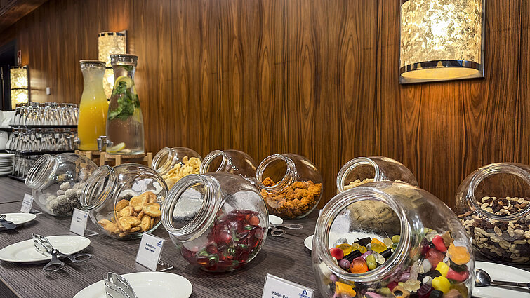 Selection of sweets, nuts, and dried fruits in jars with beverages at a coffee break at Maritim Hotel Darmstadt.