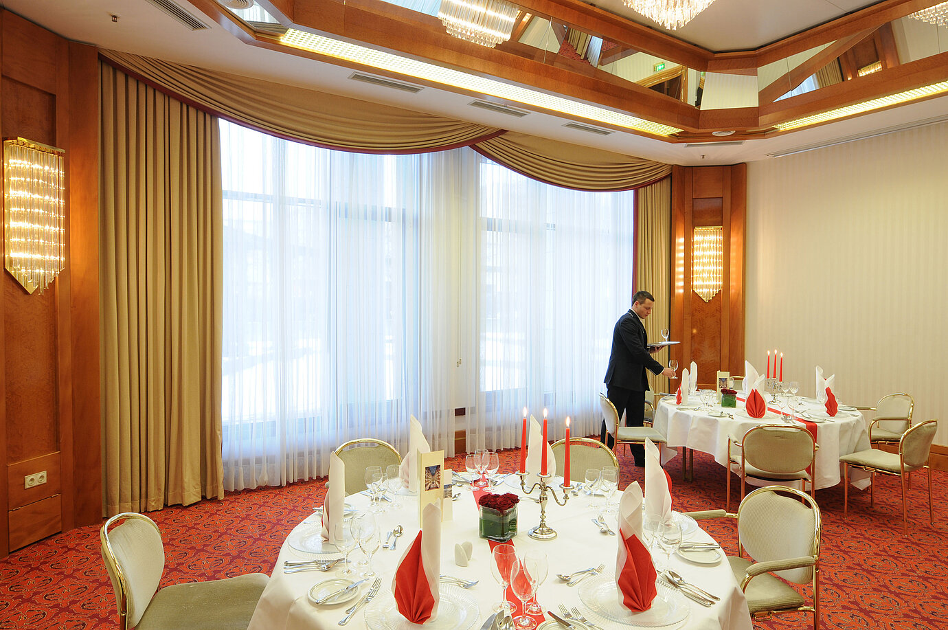 Exclusively set banquet hall with elegant candles and red napkins at Maritim Hotel Magdeburg.