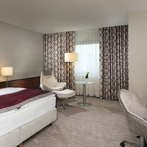 Comfort room at Maritim Hotel Bonn with cozy bed, chairs, desk, and modern curtains.