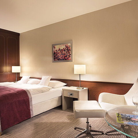 Classic room at Maritim Hotel Bonn, comfortably furnished with double bed, armchair, table, and modern lighting.