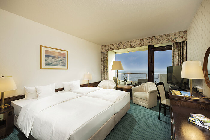 Modern hotel room at Maritim Seehotel Timmendorfer Strand with sea view from balcony, double bed, and seating area.