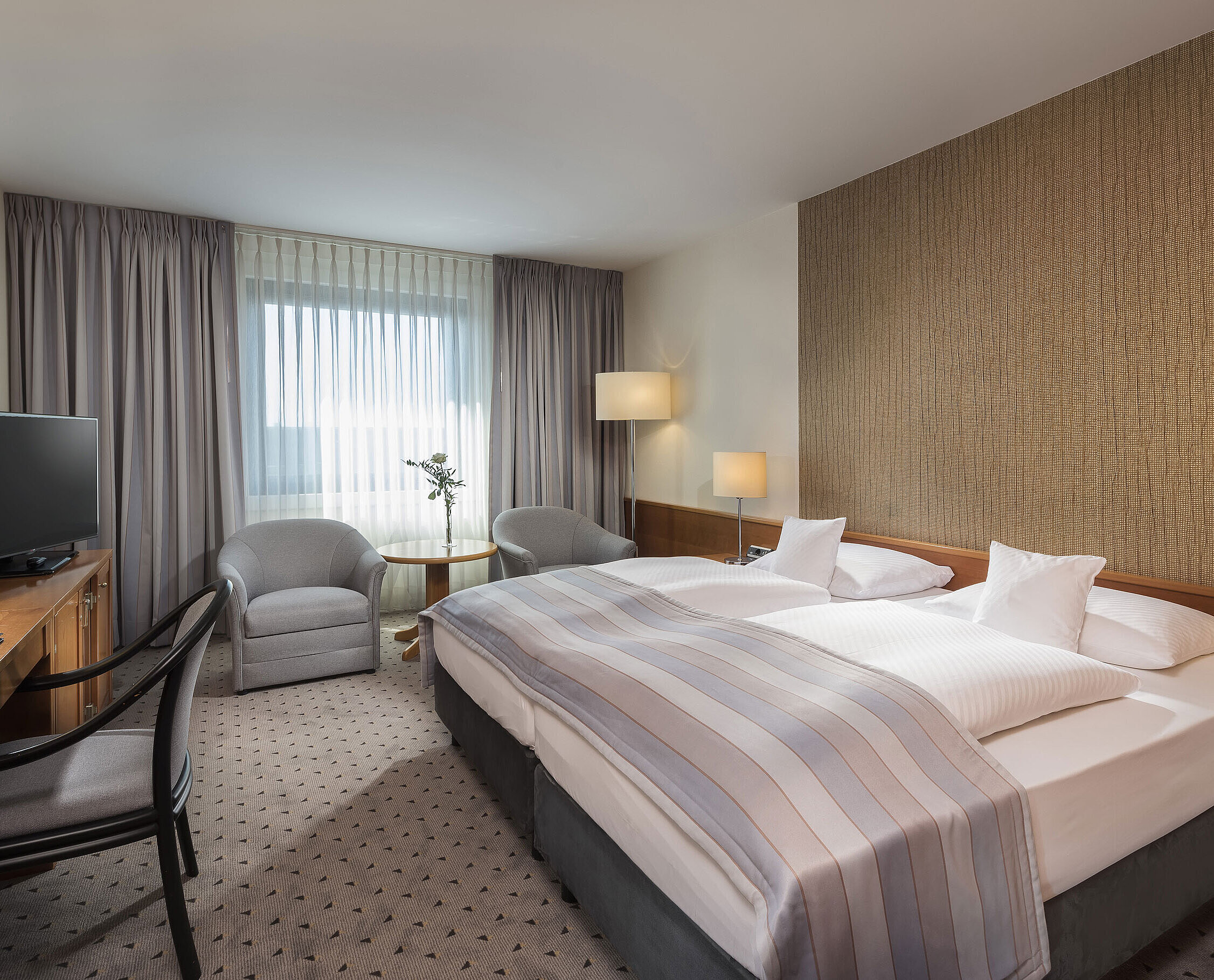 Modern classic double room with a cozy double bed, seating area, and desk at Maritim Hotel Hannover.