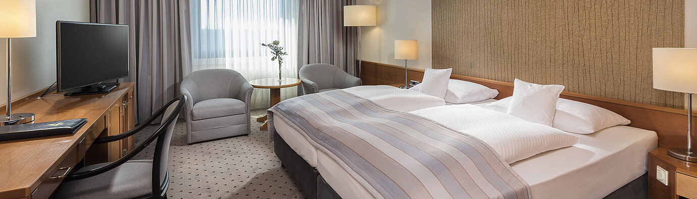 Modern classic double room with a cozy double bed, seating area, and desk at Maritim Hotel Hannover.