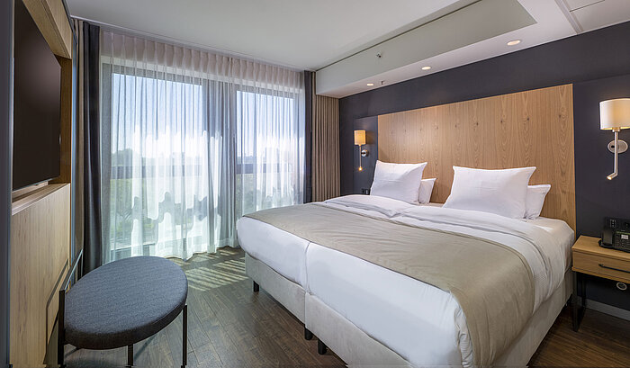 Spacious double room with modern design, comfortable beds, and city view at Maritim Hotel Ingolstadt.
