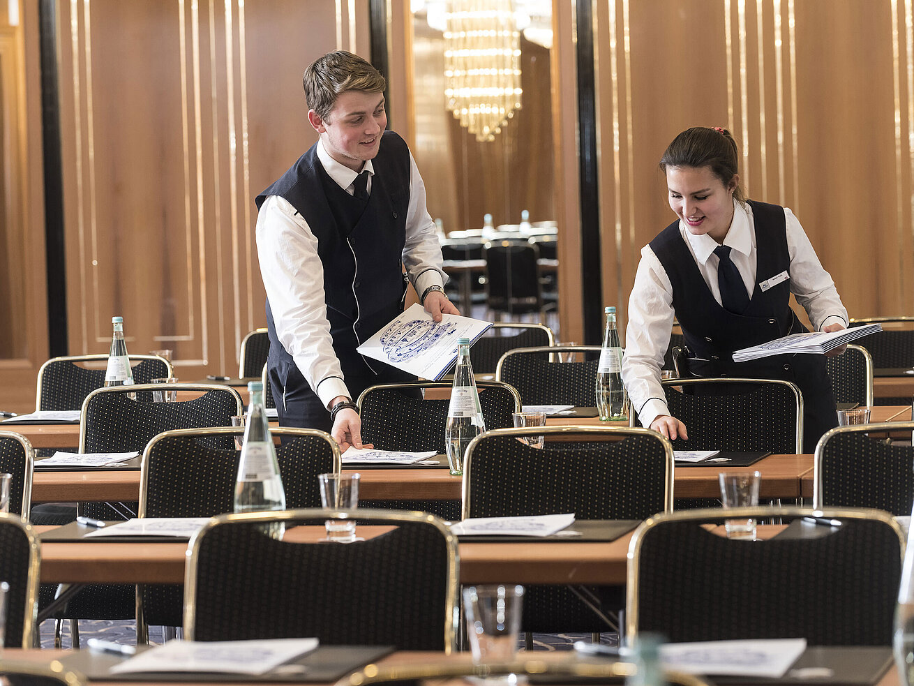 Two staff members place conference documents on tables at Maritim Hotel Stuttgart