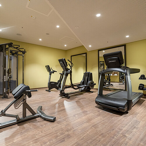 Modern gym at Maritim Hotel Ingolstadt with treadmill, dumbbells, and exercise equipment.