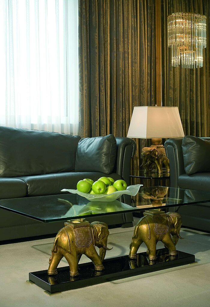 Elegant lounge with leather sofas, glass/elephant table and apples