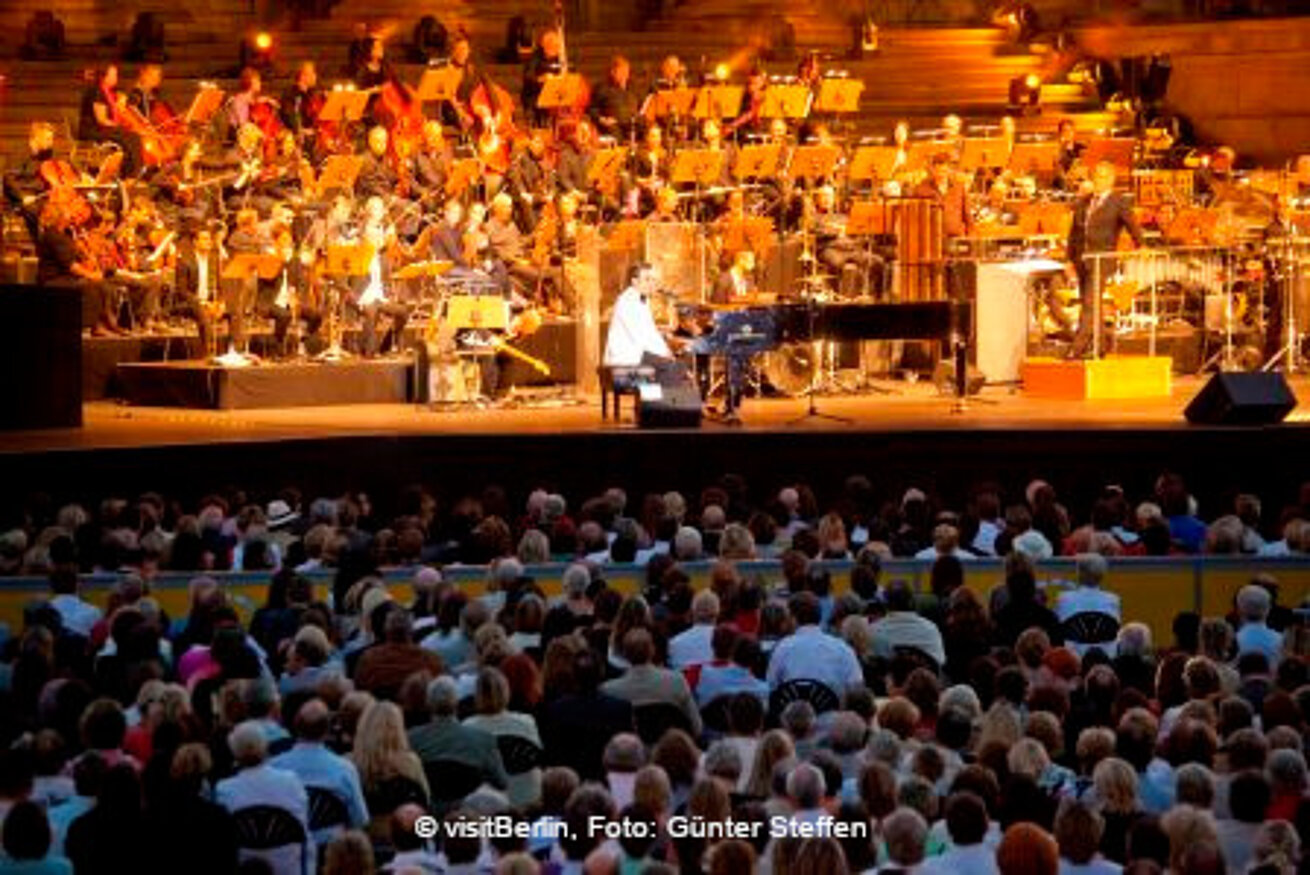 Open air concert with orchestra and audience in evening setting
