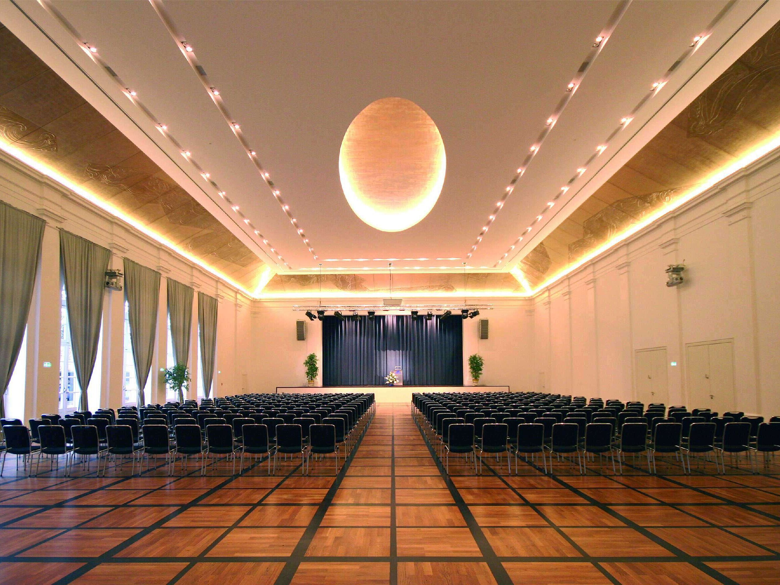 Elegant banquet hall at Maritim Hotel Fulda with a stage, stylish lighting, and seating for events.