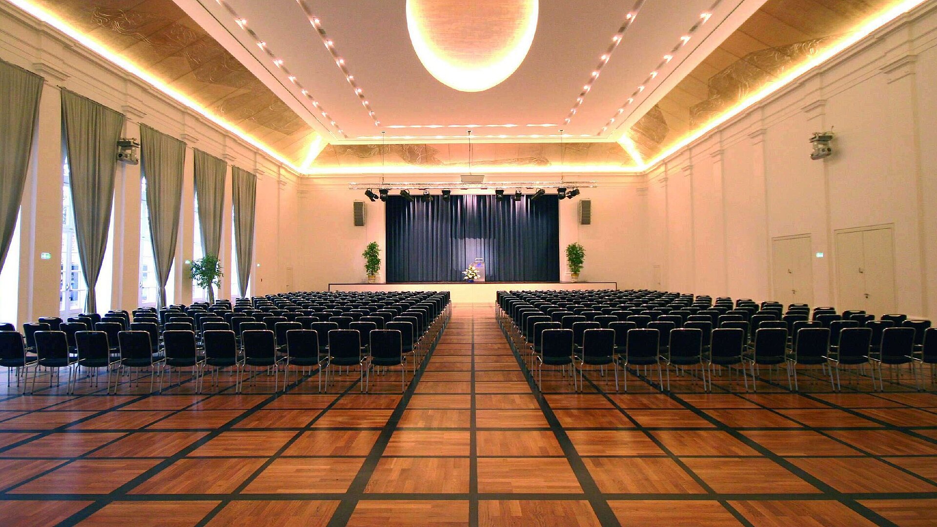 Elegant banquet hall at Maritim Hotel Fulda with a stage, stylish lighting, and seating for events.
