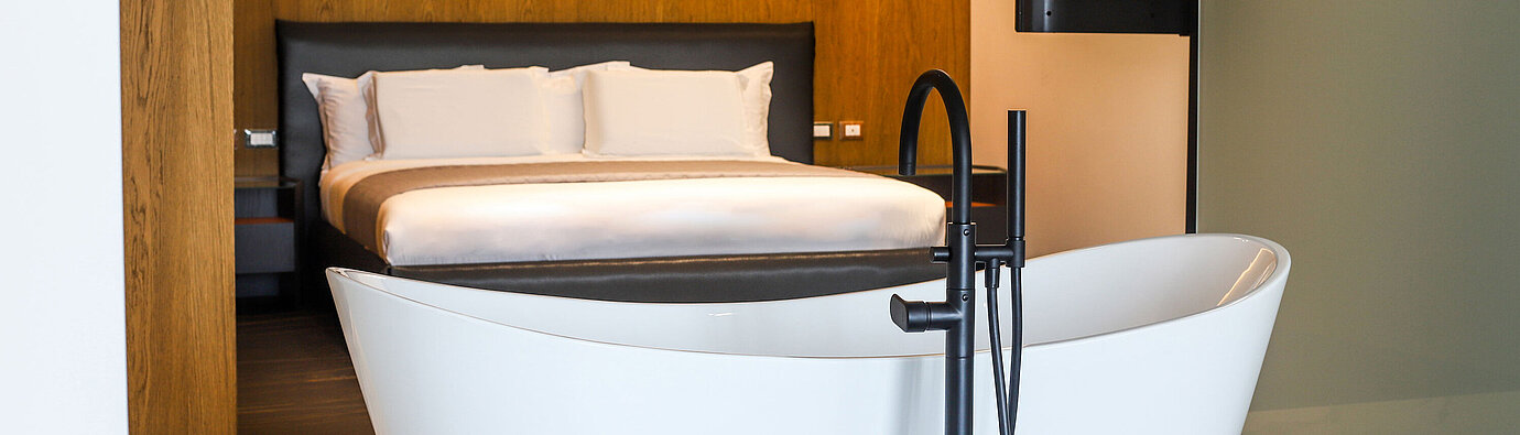 Freestanding bathtub at Maritim Resort Marina Bay facing modern bedroom with warm wood design